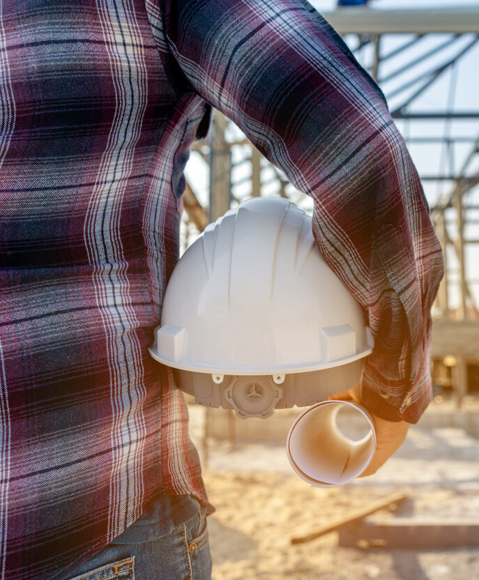 Foreman holding drawing project and holding safety helmet and looking forward to home project background concept construction working in the construction site.